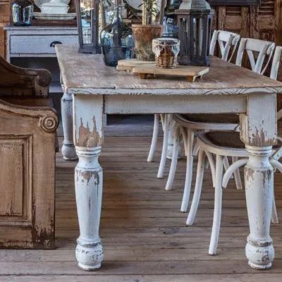 an old wooden table with chairs and vases on it in a rustic dining room