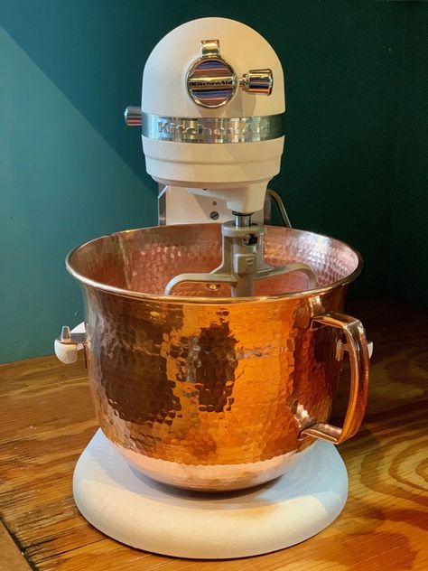 a large metal bowl on top of a wooden table next to a white and silver mixer