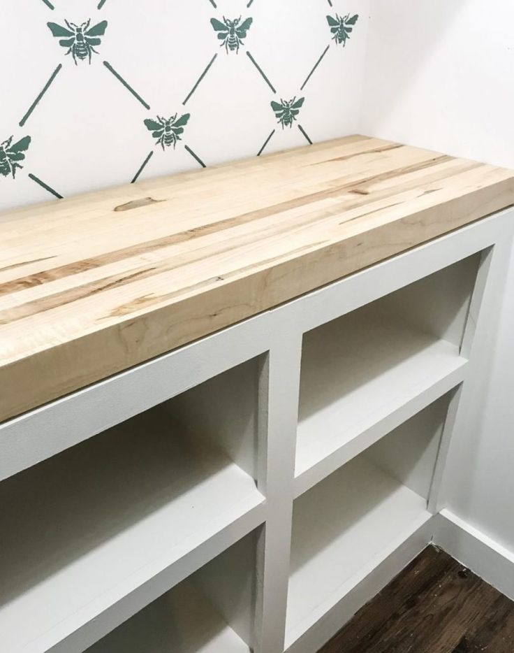 a wooden bench sitting on top of a white shelf