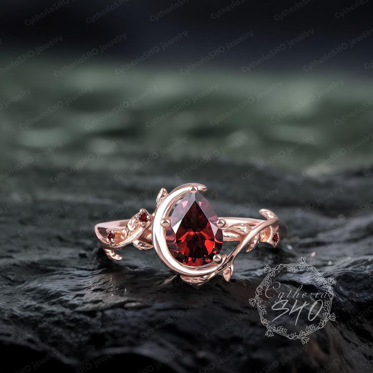 a ring with a red stone in the middle on top of a black rock and water