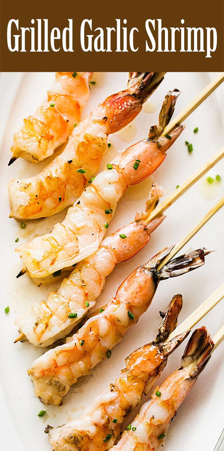 several shrimp skewers are on a white plate