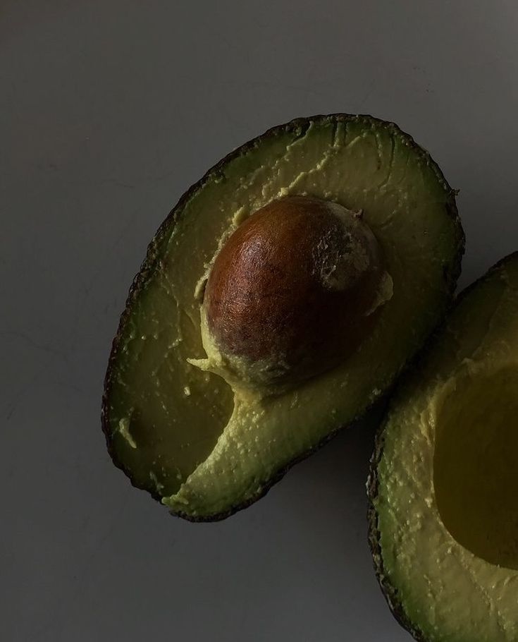 two halves of an avocado on a white surface