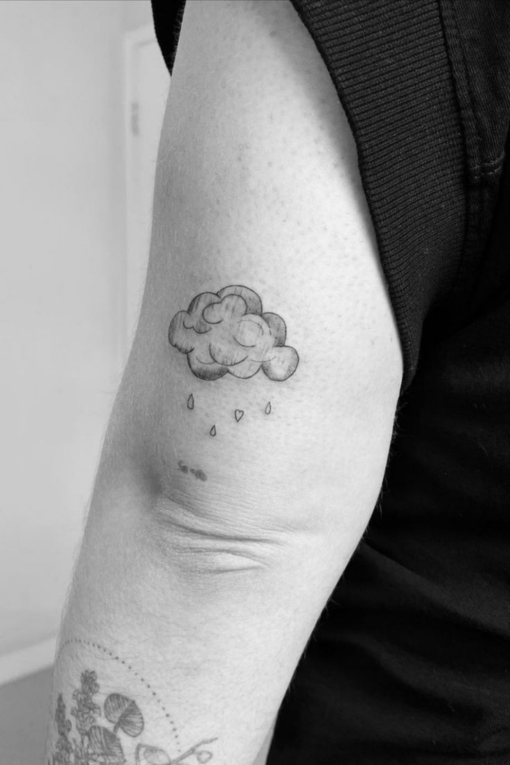 a black and white photo of a person with a cloud tattoo on their left arm