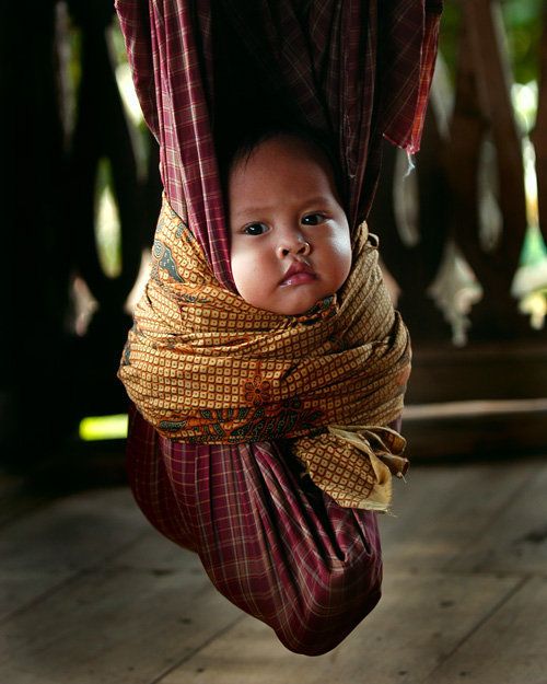 a young child hanging upside down in a hammock