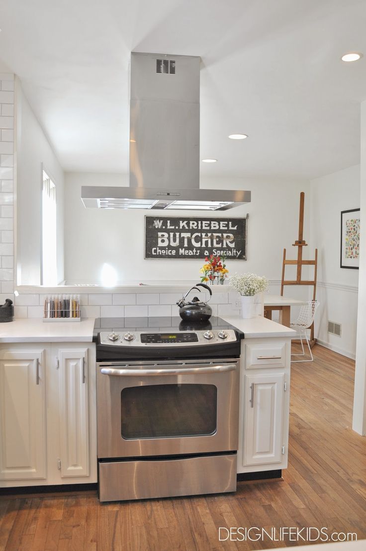 a kitchen with white cabinets and stainless steel stove top oven in the center of the room