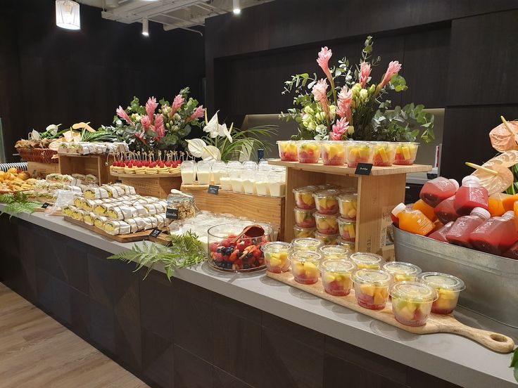 an assortment of food is displayed on a buffet table with flowers and fruit in the background