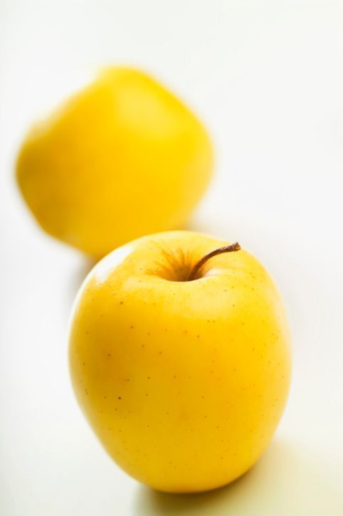 two yellow apples sitting next to each other