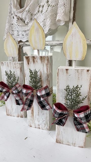 three wooden blocks decorated with christmas greenery and bows are sitting on a white table