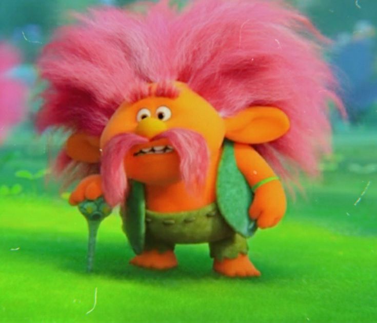 an orange troll with pink hair and green pants is standing in the middle of a field