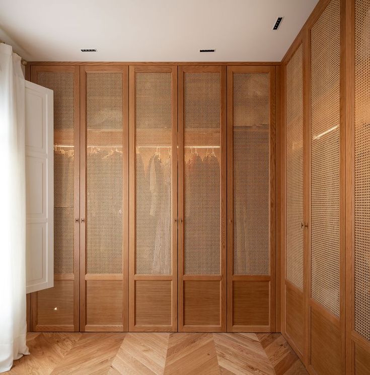 an empty room with wooden cabinets and white curtains