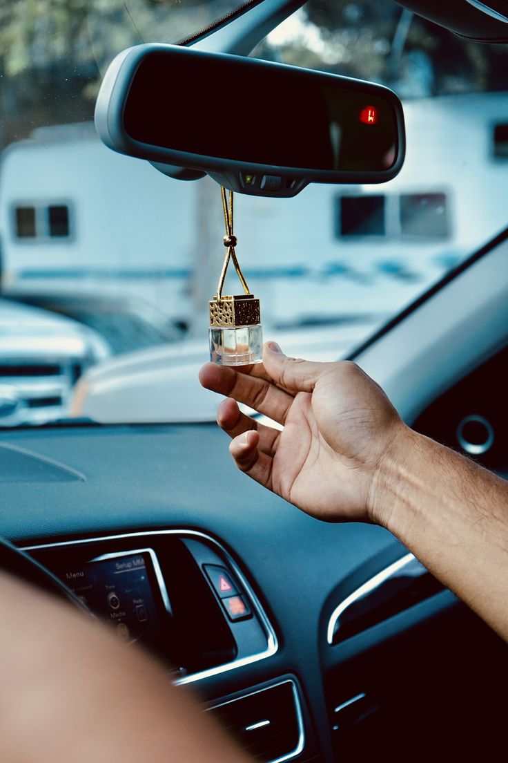 a person holding an object in their hand while sitting in the driver's seat