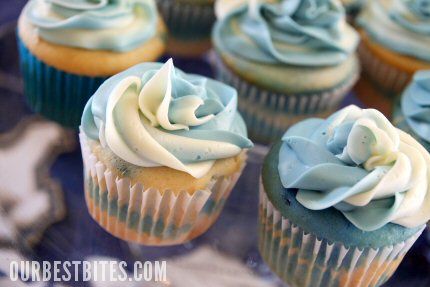 cupcakes with blue frosting and white icing on top are sitting on a glass plate