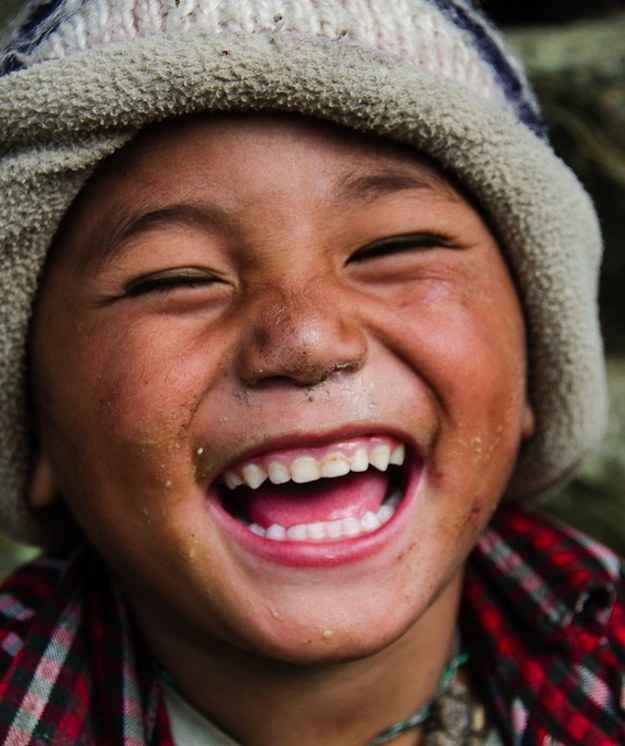 a young boy smiling and wearing a hat on top of his head with dirt all over his face