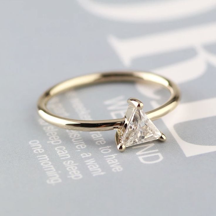 a gold ring with a princess cut diamond in the center on top of a sheet of paper