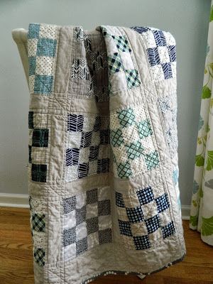 a quilted blanket sitting on top of a wooden floor next to a window with curtains