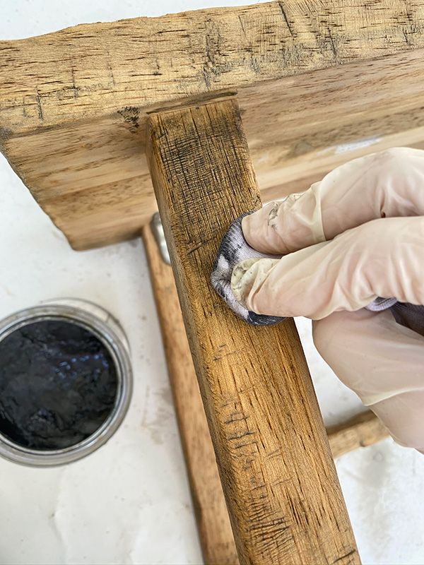 a person with gloves and rubber on their feet is painting a wooden bench in front of a dog bowl