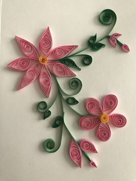 paper quilled flowers are arranged on a white surface