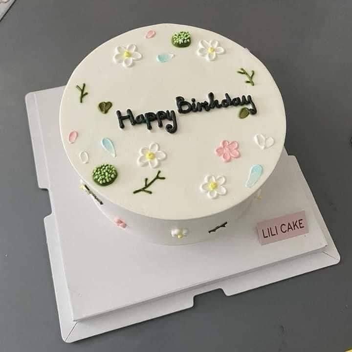 a white birthday cake with flowers and the words happy birthday on it's side