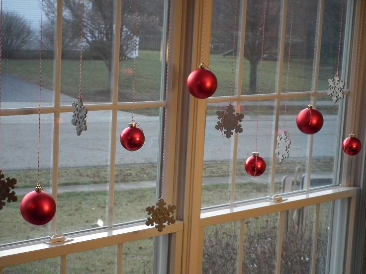 two windows with ornaments hanging from them in the window sill, one red and one silver