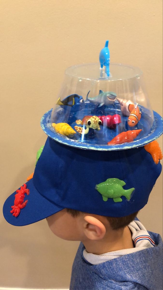 a young boy wearing a blue hat with toy fish in it's centerpiece