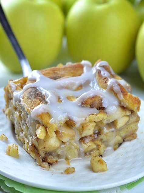 a piece of cake on a plate with apples in the background