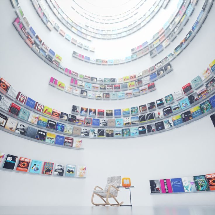 a chair sitting in front of a wall filled with lots of different kind of books