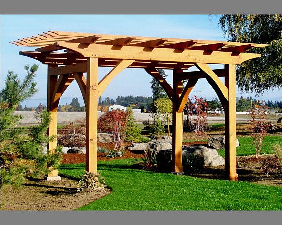 a wooden pergola in the middle of a grassy area