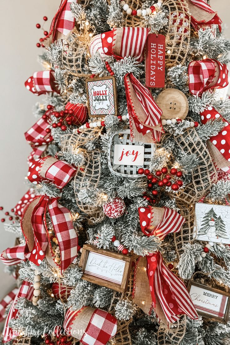 the christmas tree is decorated with red and white ribbons, plaid bows, wooden tags, and buttons