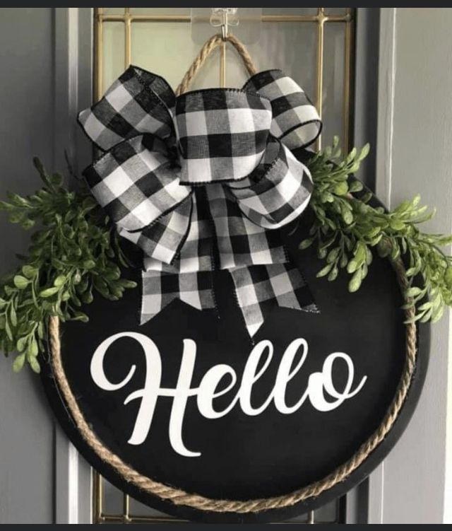 a black and white wreath with the word hello painted on it hanging from a door