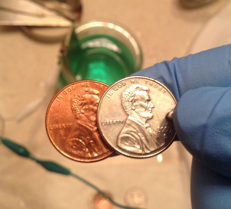 a person holding two different coins in their hand, one is green and the other is red