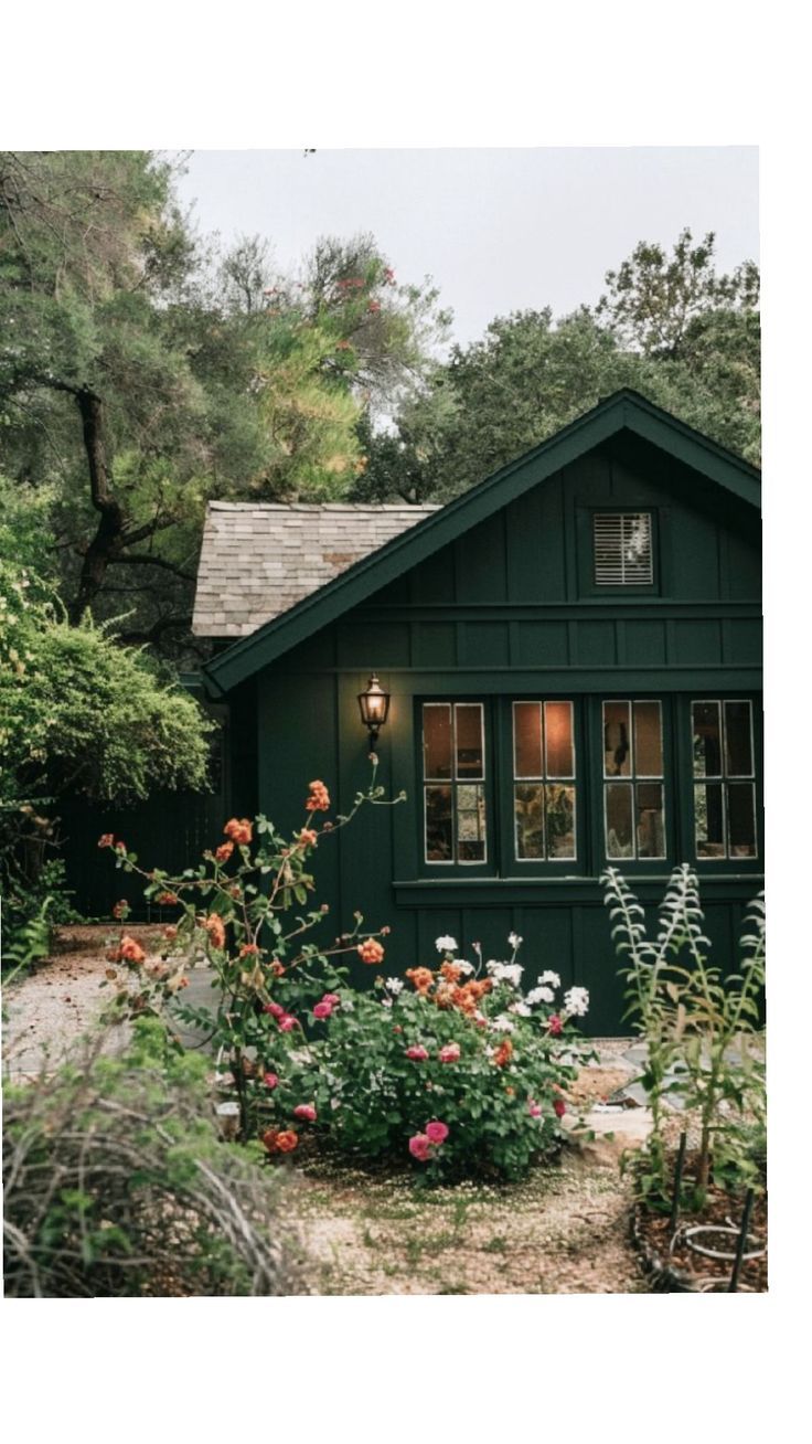 a green house surrounded by trees and flowers