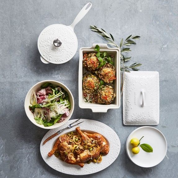 a table topped with plates and bowls filled with food next to utensils on top of a gray surface