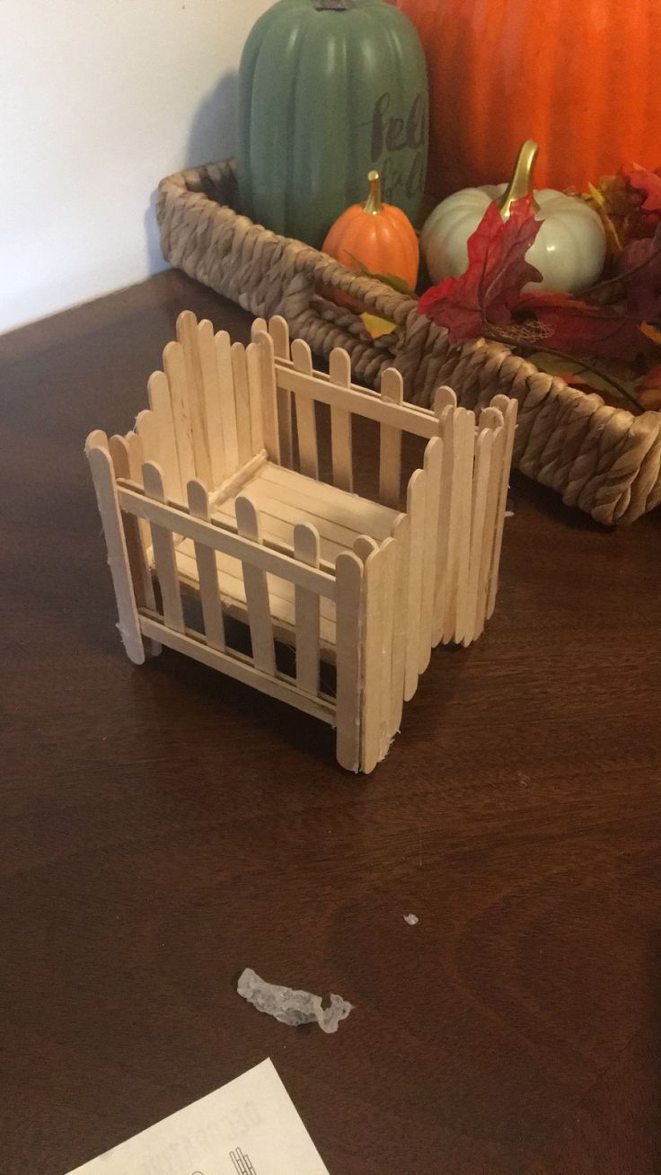 a wooden fence sitting on top of a table next to a basket filled with pumpkins