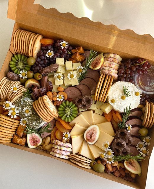 an assortment of cheeses, crackers and grapes in a wooden box on a table