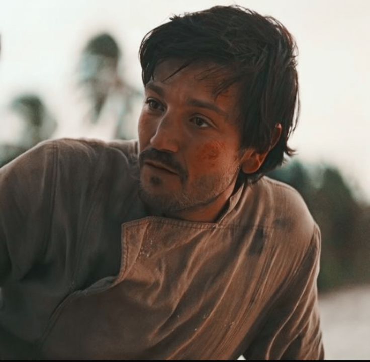 a man sitting on the side of a road with his hand on his hip and looking off into the distance