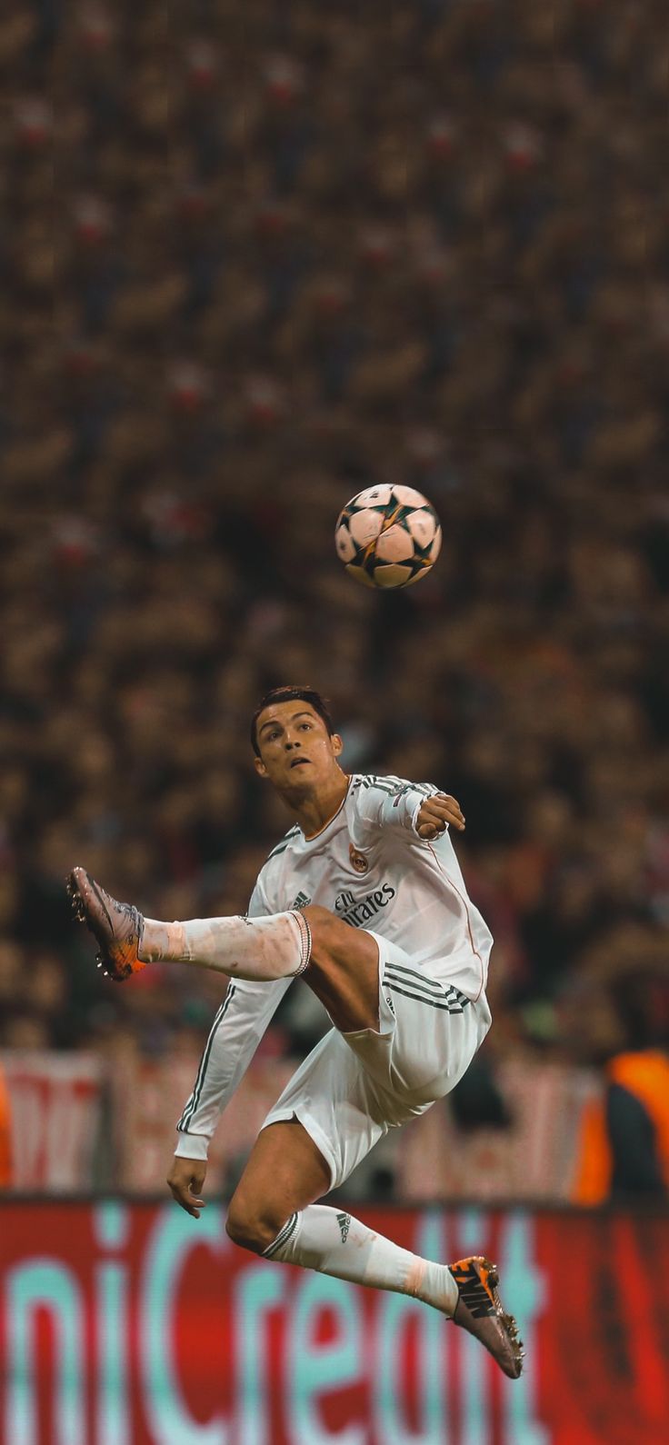 a soccer player in mid air with the ball above his head as he kicks it