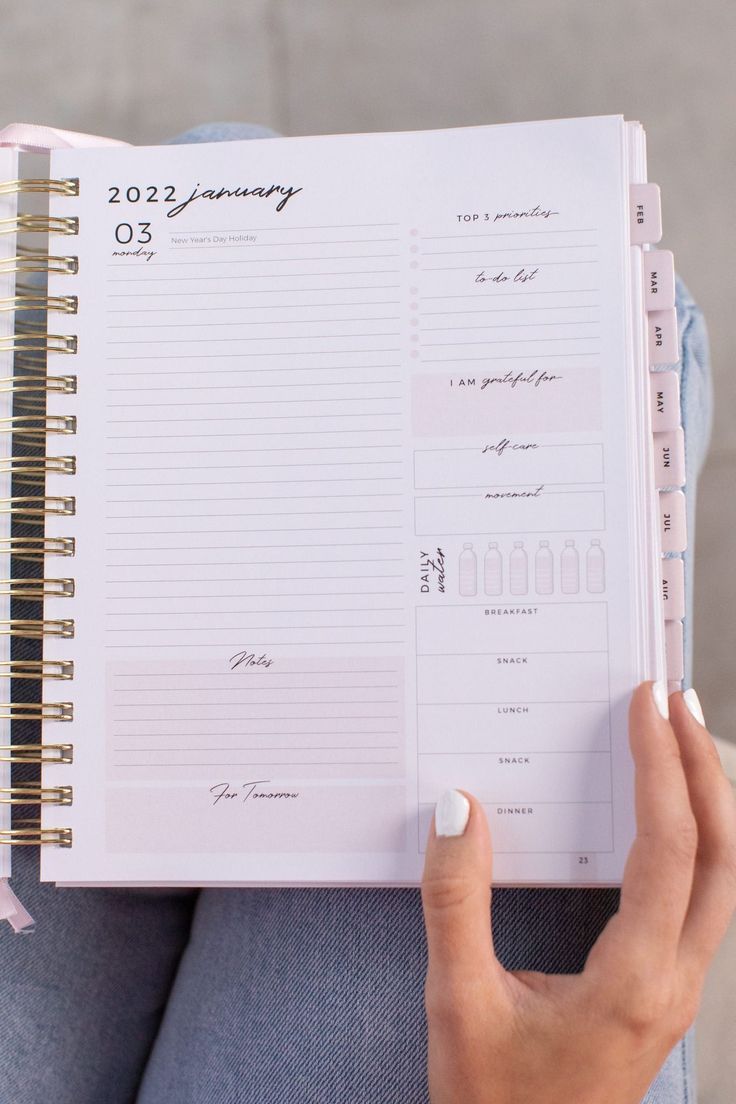 a woman is holding a planner in her hand and looking at the pages on it