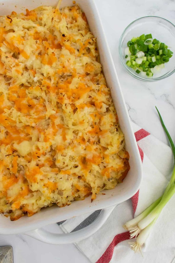 a casserole dish with cheese, onions and green onions next to it on a towel