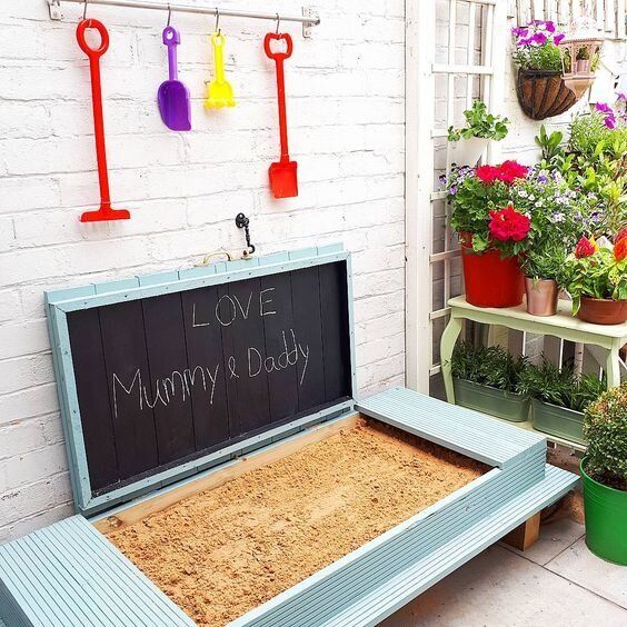 a bench with a message written on it in front of potted plants and hanging utensils