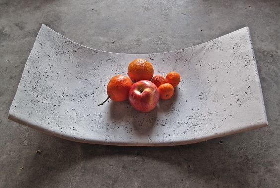 a white plate topped with fruit on top of a cement floor covered in cracks and dirt