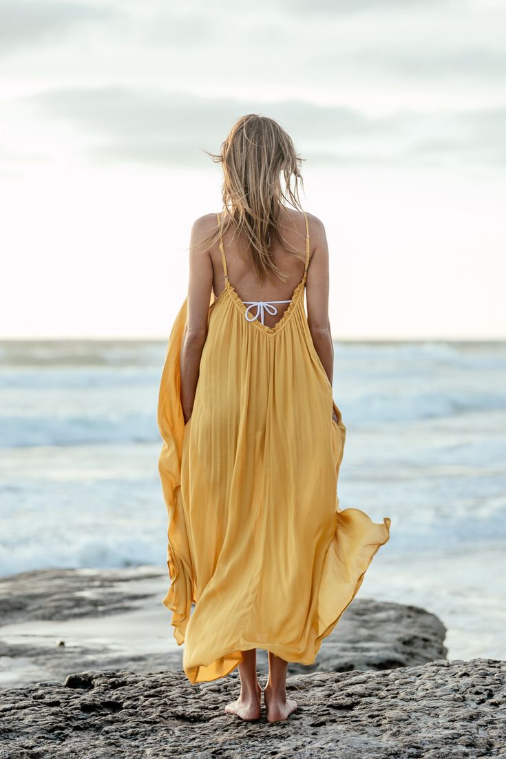 The Marigold Amalie Maxi Coverup is a dreamy beach dress for your next island-hopping adventure. The adorable ruffle neckline and deep V back have adjustable straps to accommodate your fit and make you feel a little sassy and confident. Complete with pockets large enough for your resort key and some lip gloss and in a gorgeous marigold color. Adjustable straps Machine washable Pockets! 100% rayon Our XS/S size is best for people 5'4 and under. Chic Gold Swimwear For Summer, Chic Gold Swimwear For The Beach, Backless Poolside Cover-up For Beach Season, Backless Poolside Beach Cover-up, Gold Sleeveless Swimwear For Pool, Gold Beachwear Swimwear For Spring, Chic Gold Beach Dress, Gold Summer Swimwear, Beachy Dresses For Sunbathing Vacation