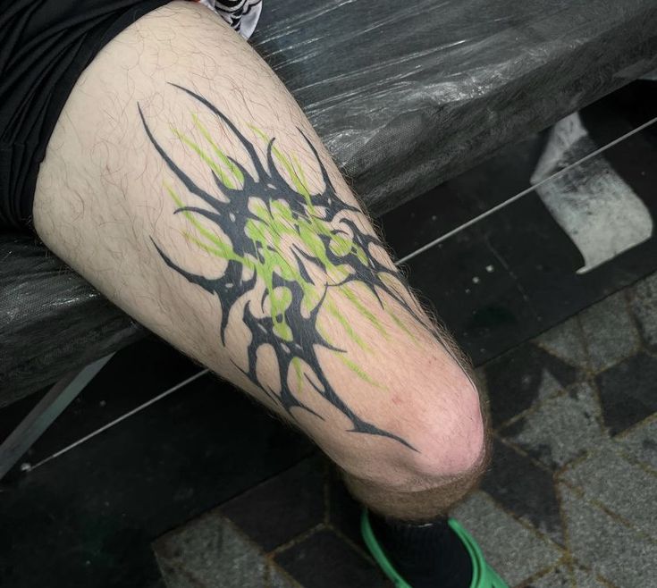 a man with green and black tattoos on his legs