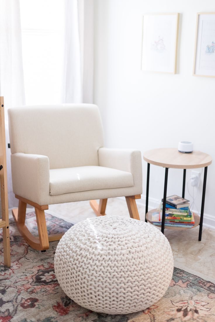 a white chair and ottoman in a small living room with a rug on the floor