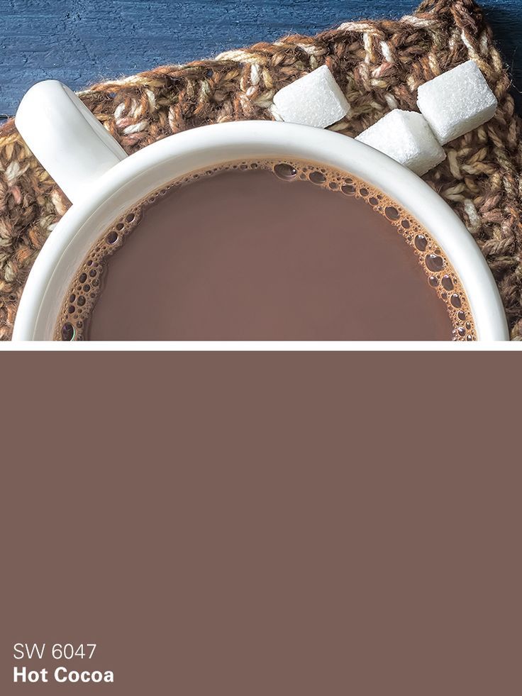 a cup of hot chocolate with marshmallows on the side and a crocheted place mat