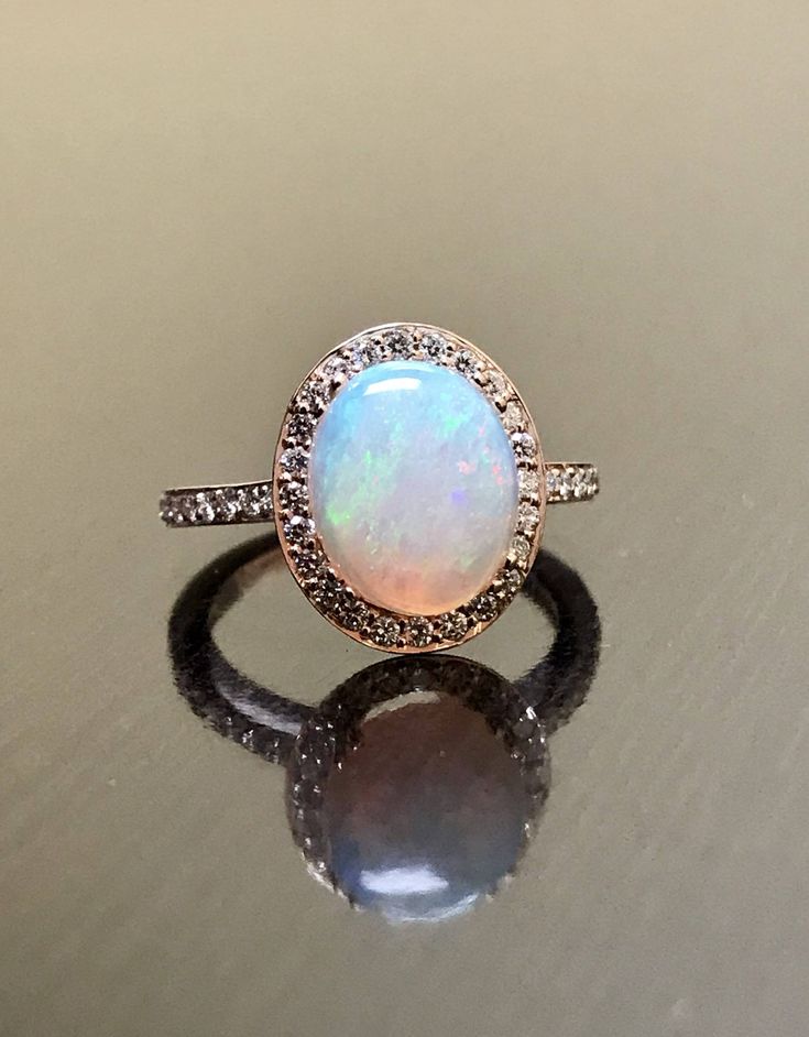 an opalite and diamond ring sits on a reflective surface