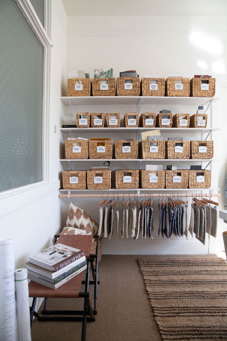 an organized closet with baskets and clothes hanging on the wall next to a bench in front of a window