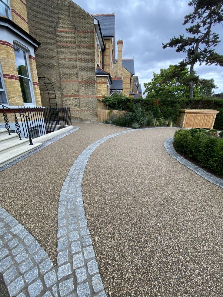 a curved driveway with cobblestones in front of a house