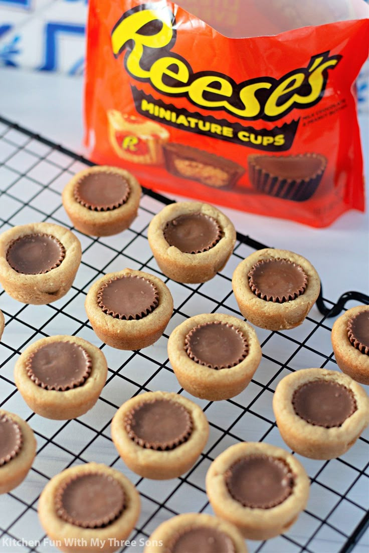 peanut butter cupcakes on a cooling rack next to a bag of reese's