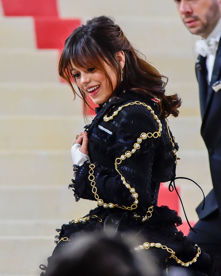 a woman in a black dress is walking down the stairs with her hand on her hip