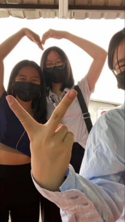 three women wearing face masks making the shape of a v with their hands in front of them